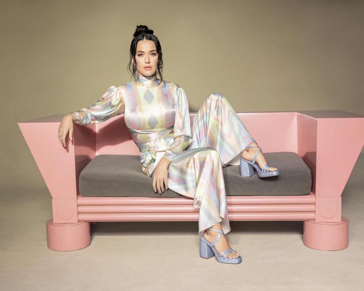 Певица Кэти Перри сидит на розовом диване