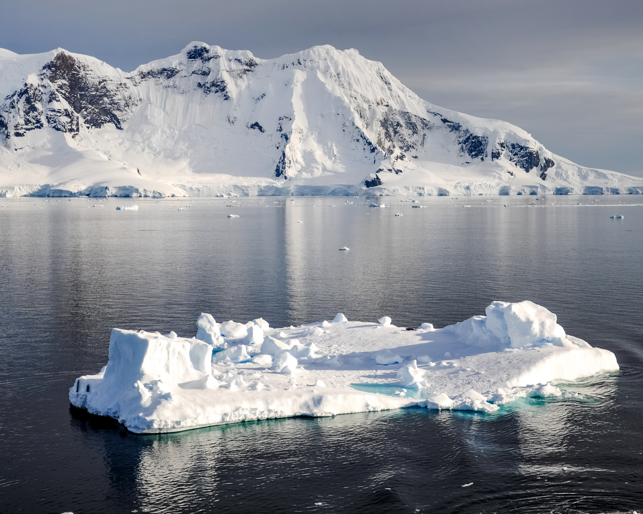 Холодный айсберг в воде у заснеженных гор, Антарктика
