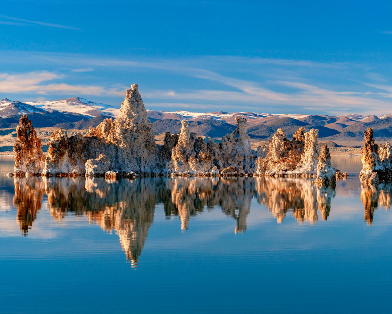 Острые скалы отражаются в тихой воде озера