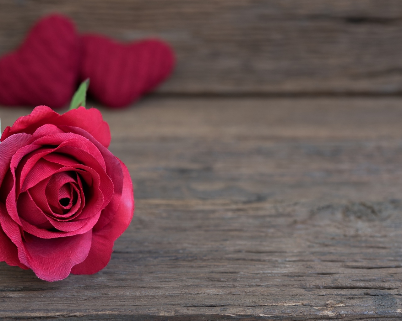 Искусственная роза на деревянном фоне с сердечками