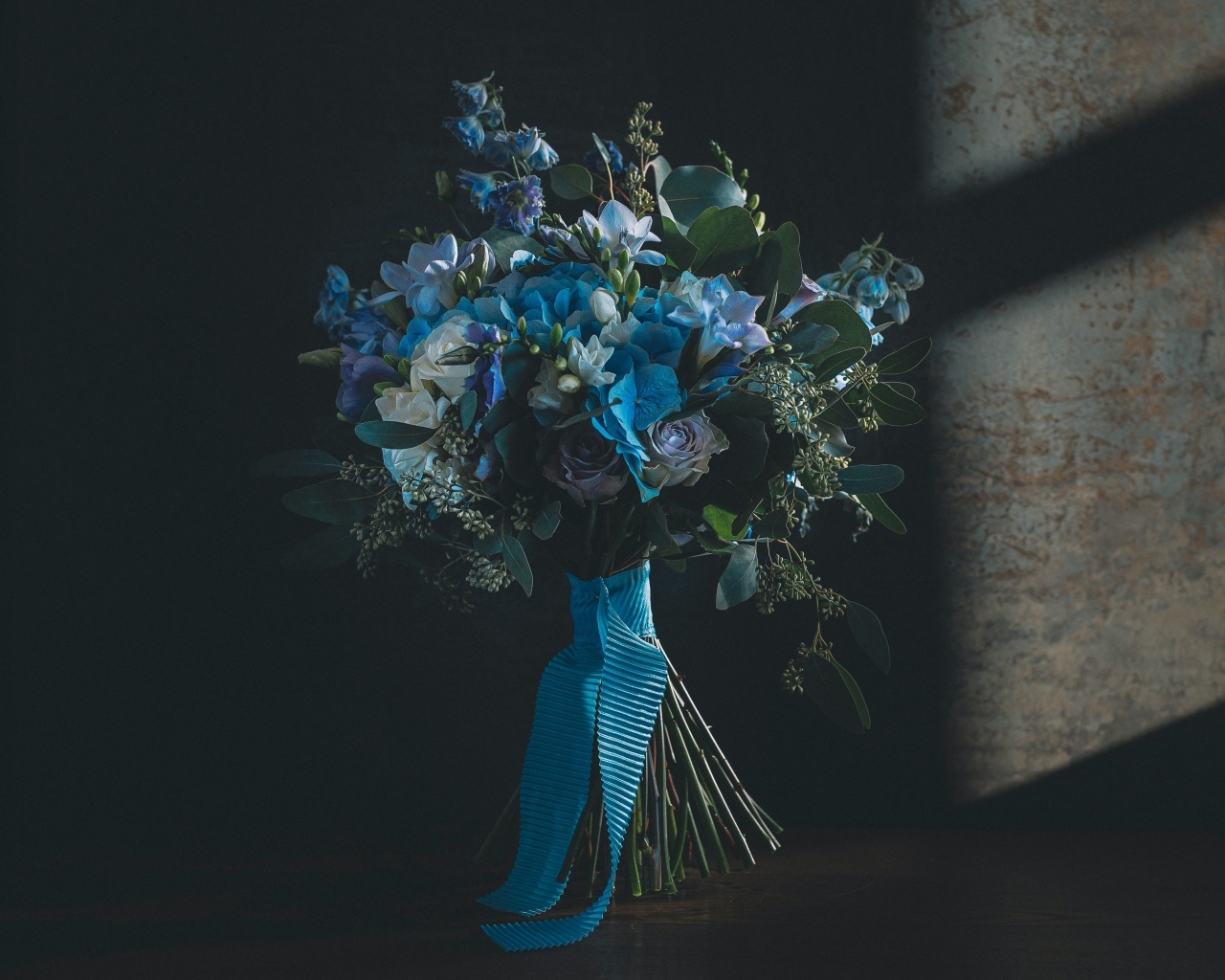 Красивый букет цветов с голубой лентой у стены