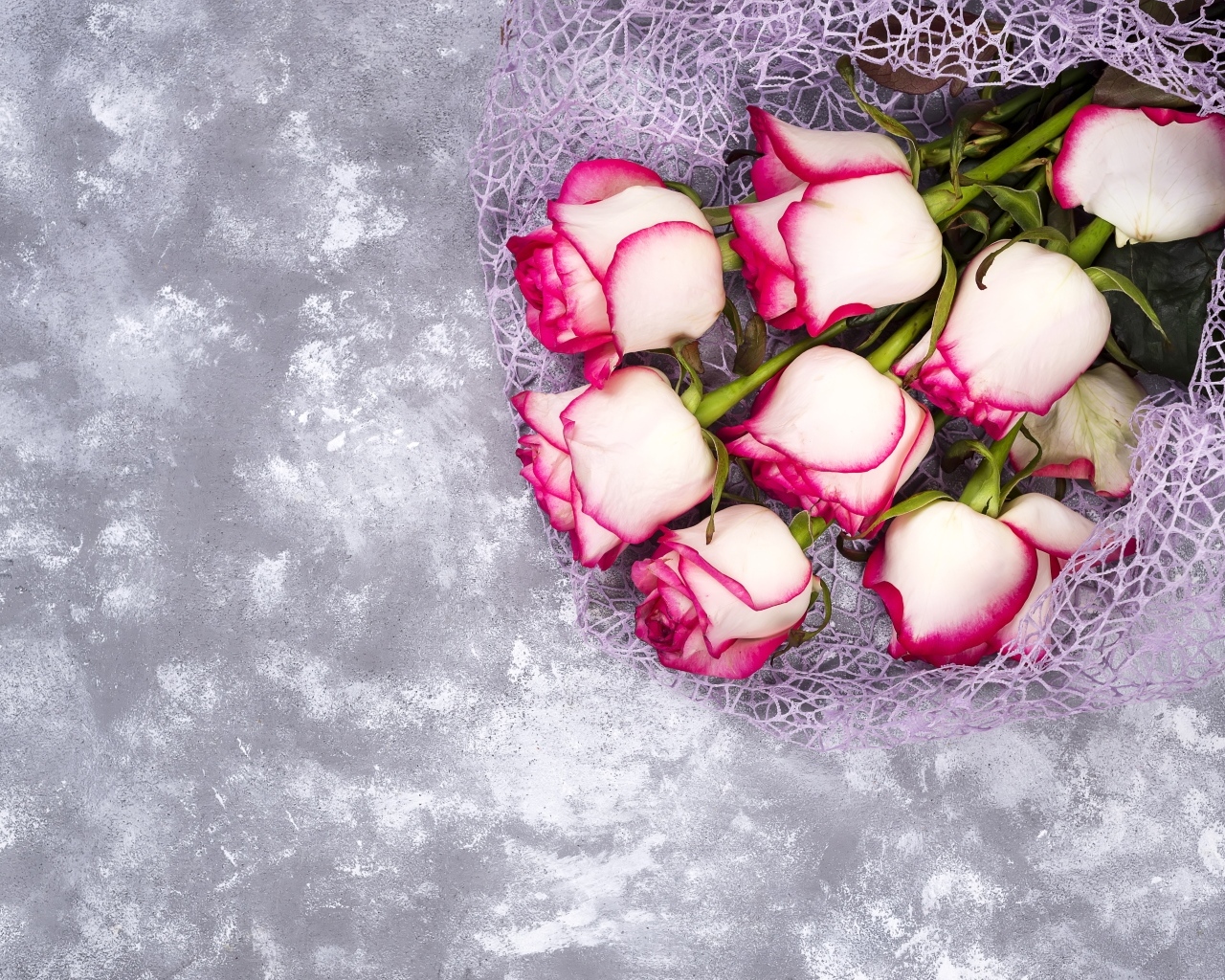 Красивый букет роз в упаковке на сером столе