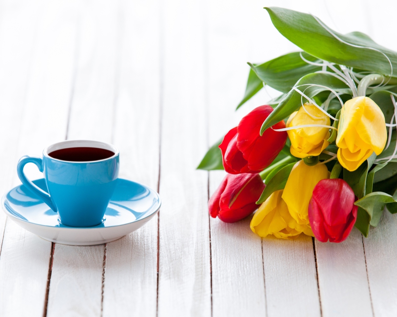 Голубая чашка на столе с букетом тюльпанов