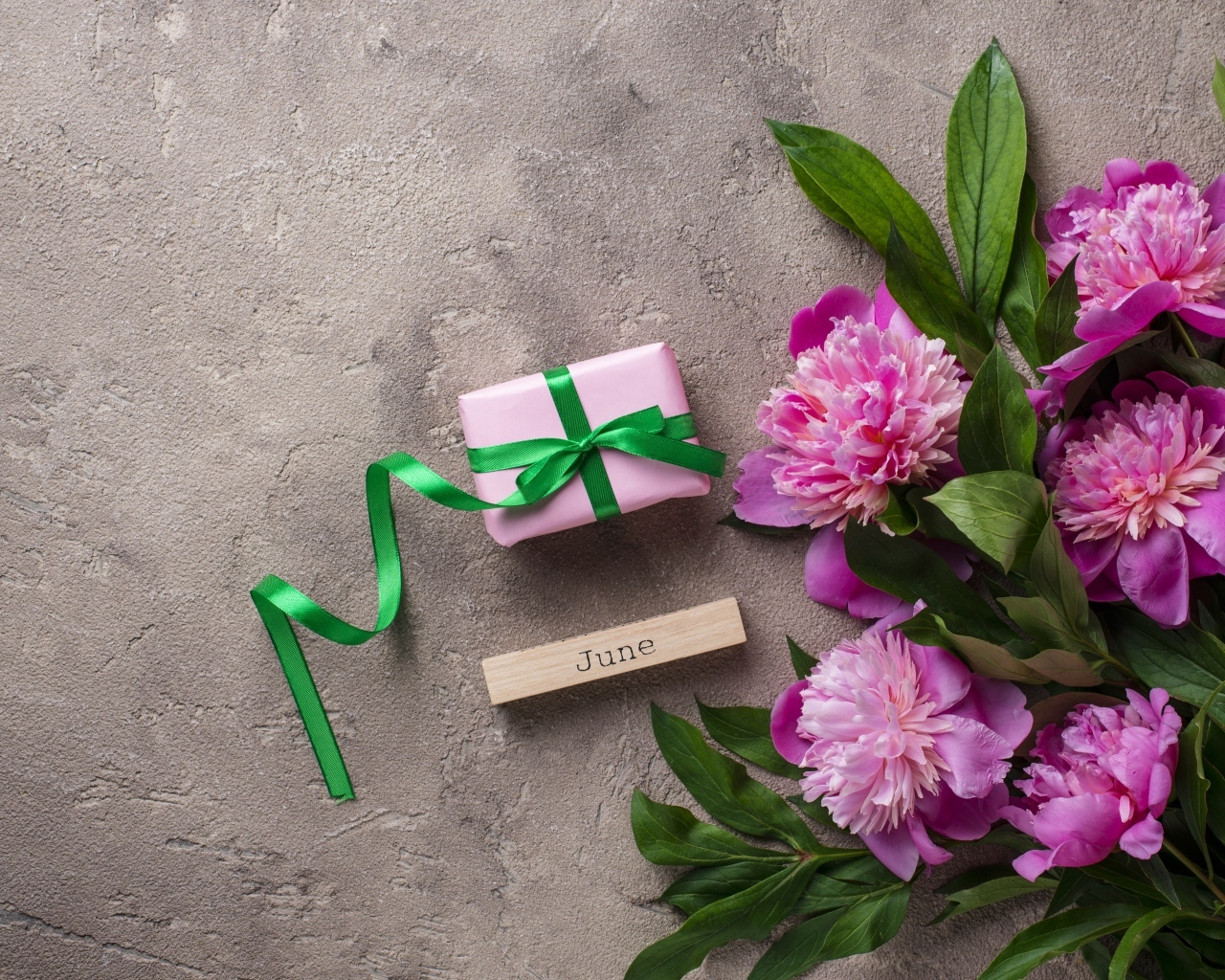 Букет розовых пионов с подарком на сером столе