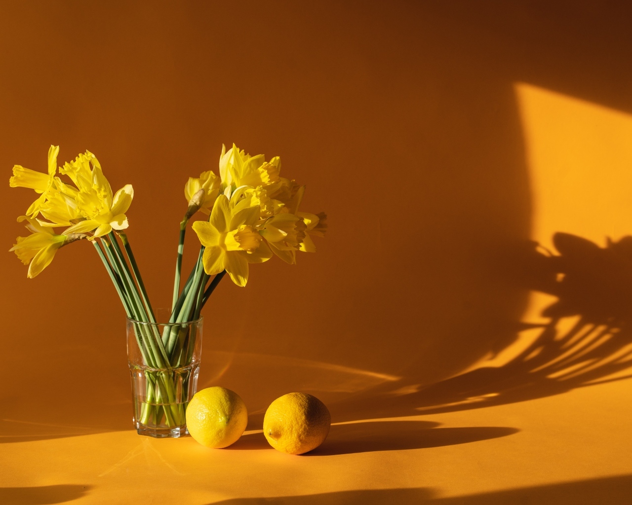 Букет желтых нарциссов в вазе на столе с лимонами