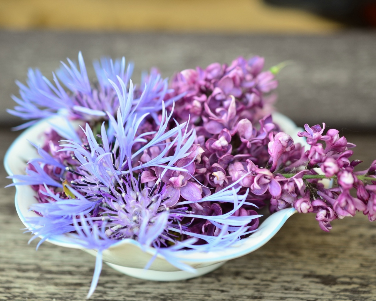 Цветы сирени и василька в вазе на столе