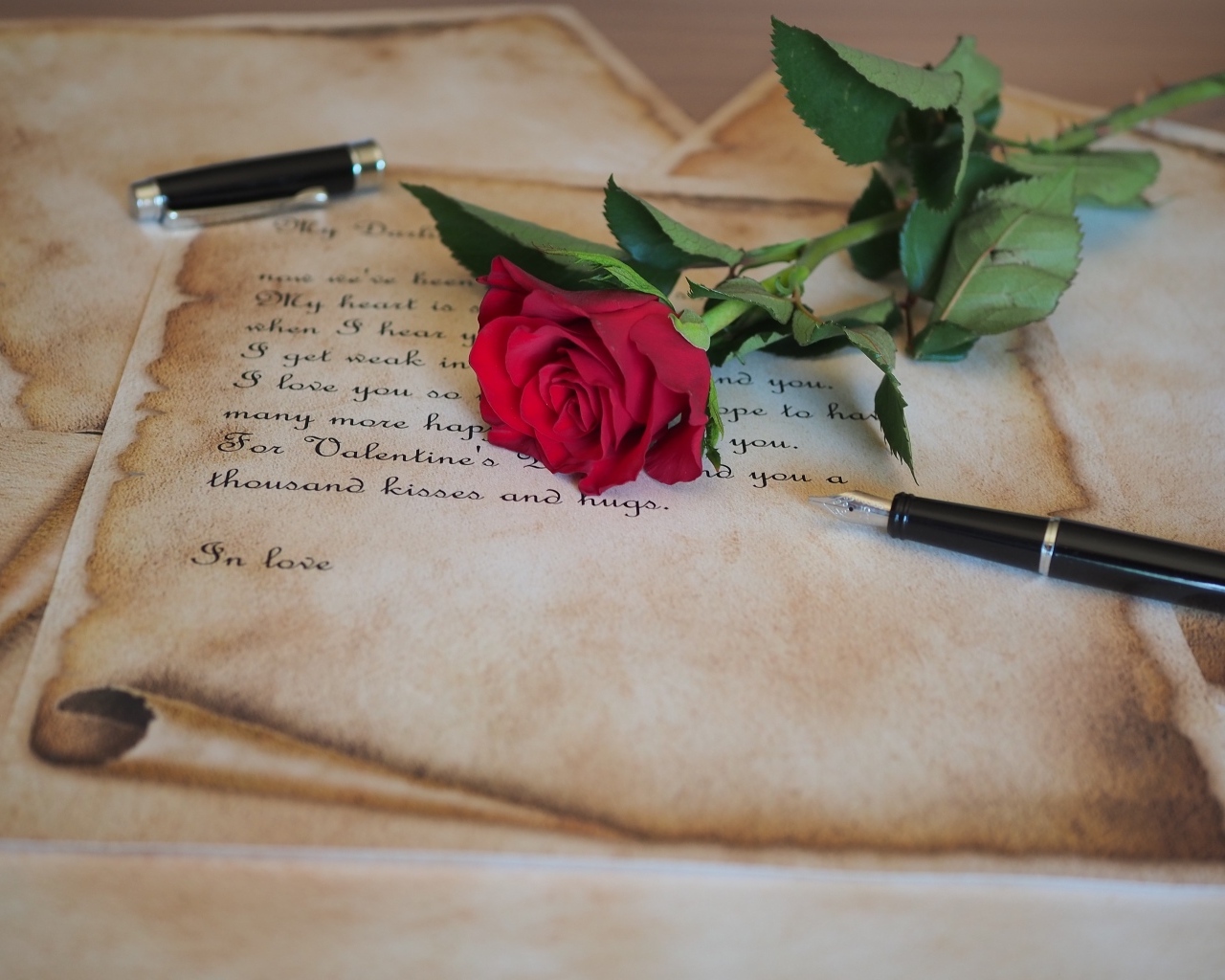 Красная роза с запиской и ручкой на столе
