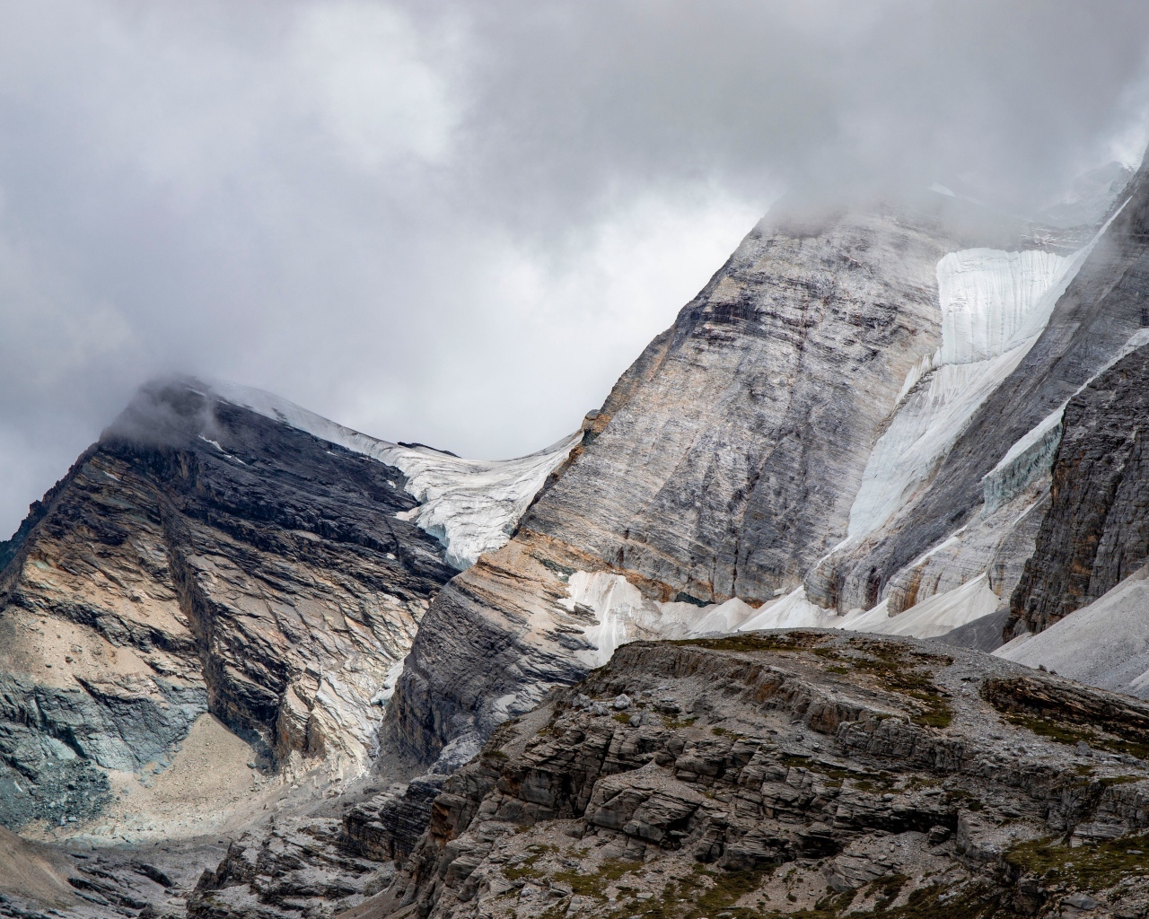Высокие каменные горы в белых облаках