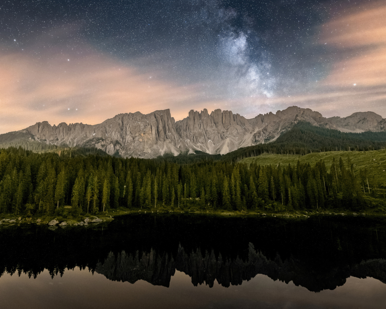 Млечный путь над горами и лесом отражающимися в воде