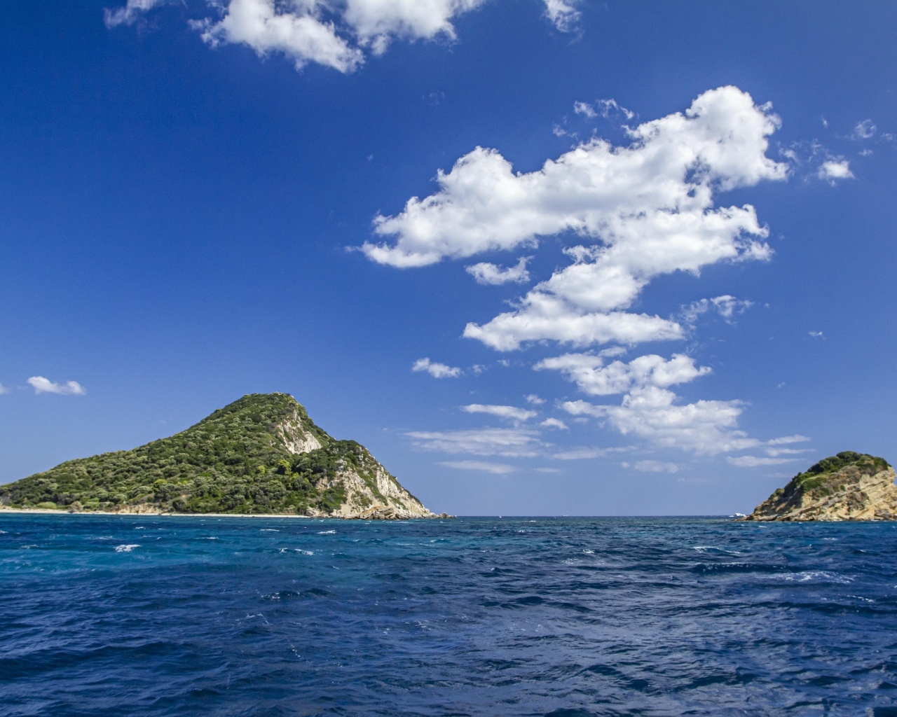 Покрытые зеленью горы в море под голубым небом