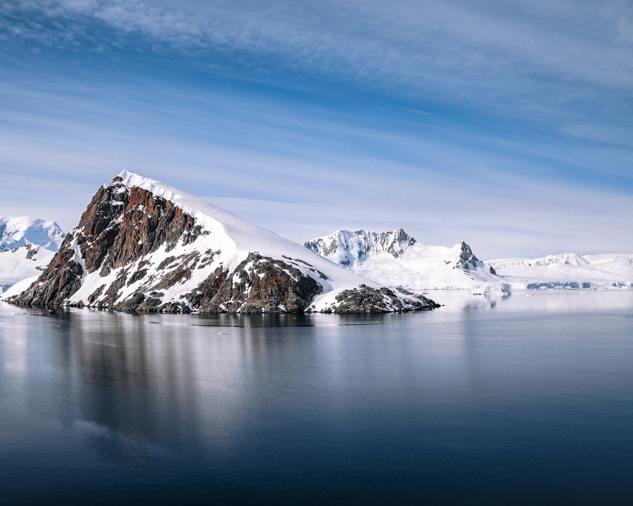 Заснеженная гора на берегу моря под голубым  небом
