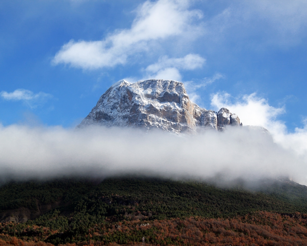 Заснеженная горная вершина в белых облаках