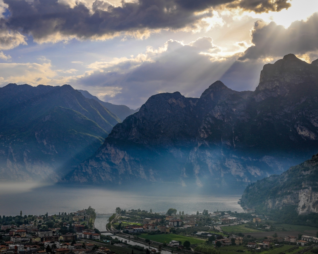 Лучи солнца покрывают горы и город 