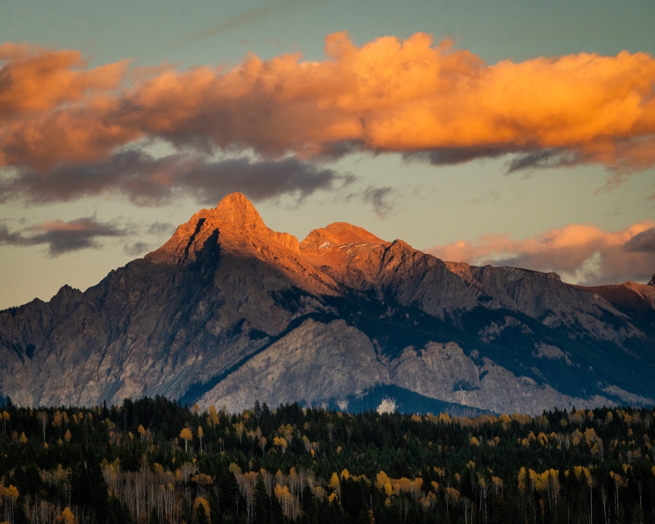 Солнце в облаках освещает вершину горы