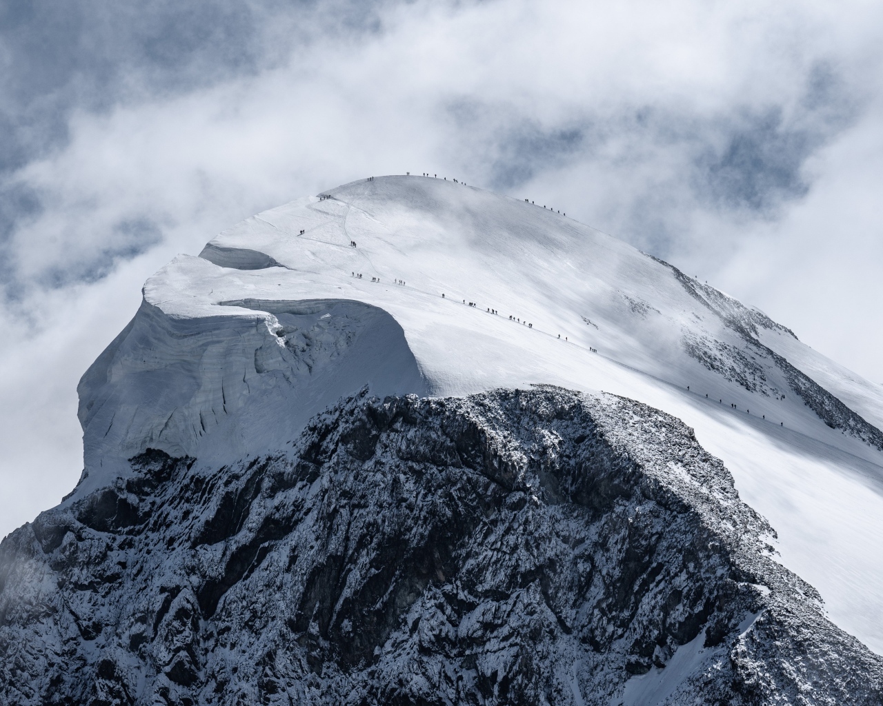 Вид на заснеженную вершину горы под белыми облаками