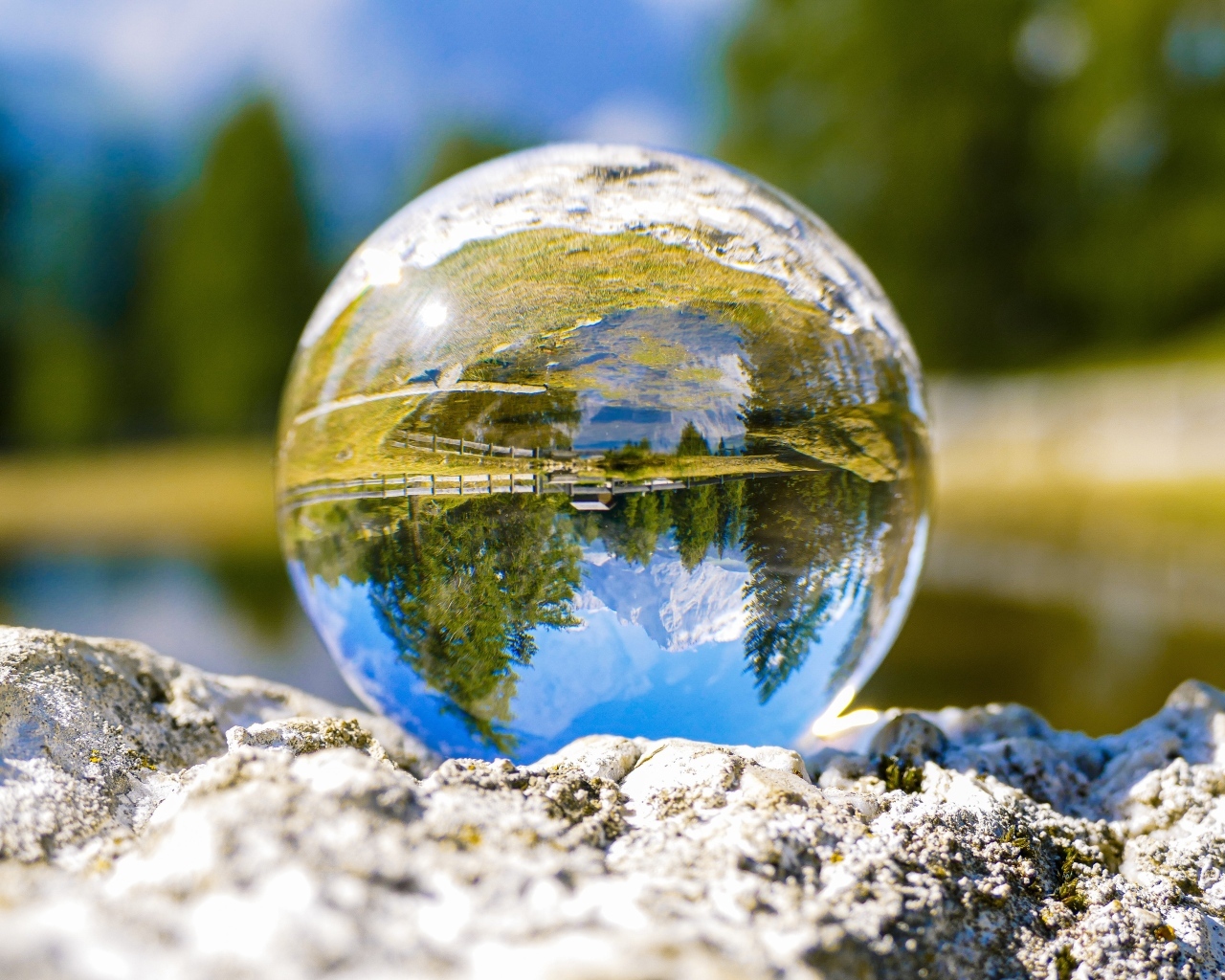 Стеклянный шар стоит на камне у воды