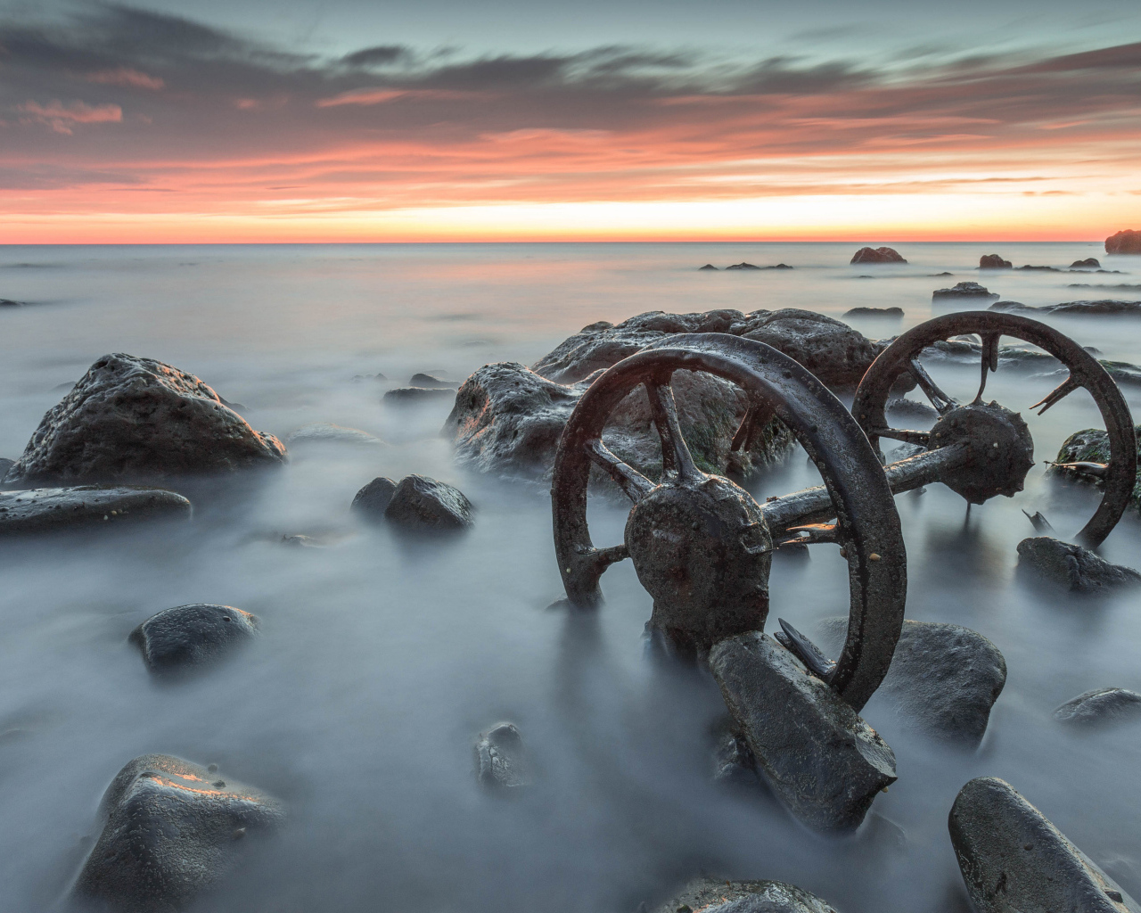 Старые колеса лежат в воде с камнями