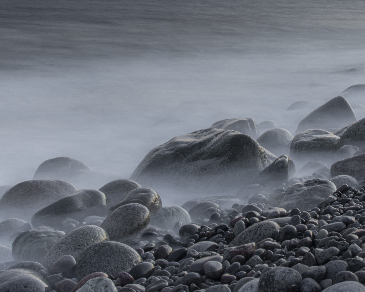 Большие черные камни на берегу моря в тумане