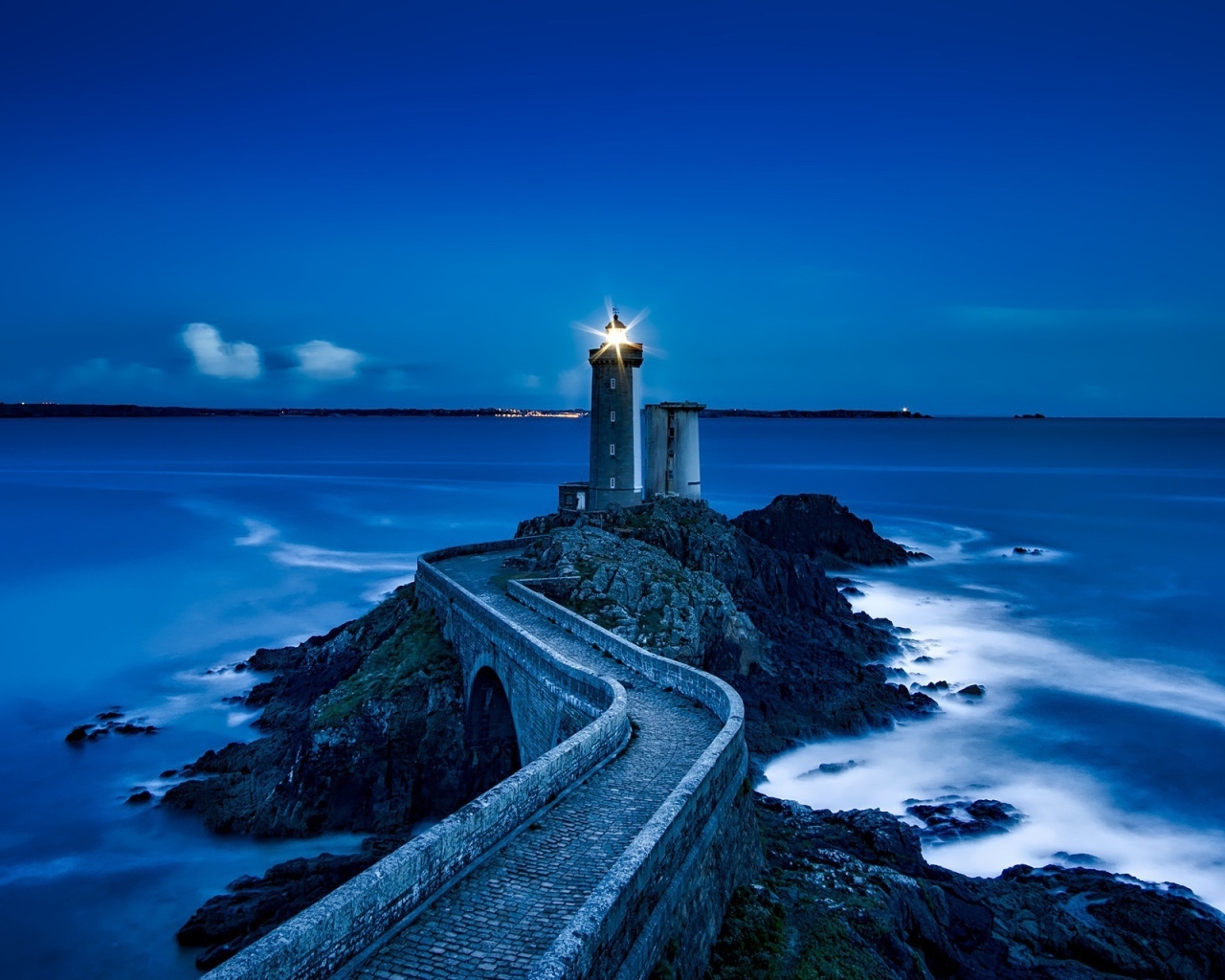 Зажженный маяк на берегу моря ночью