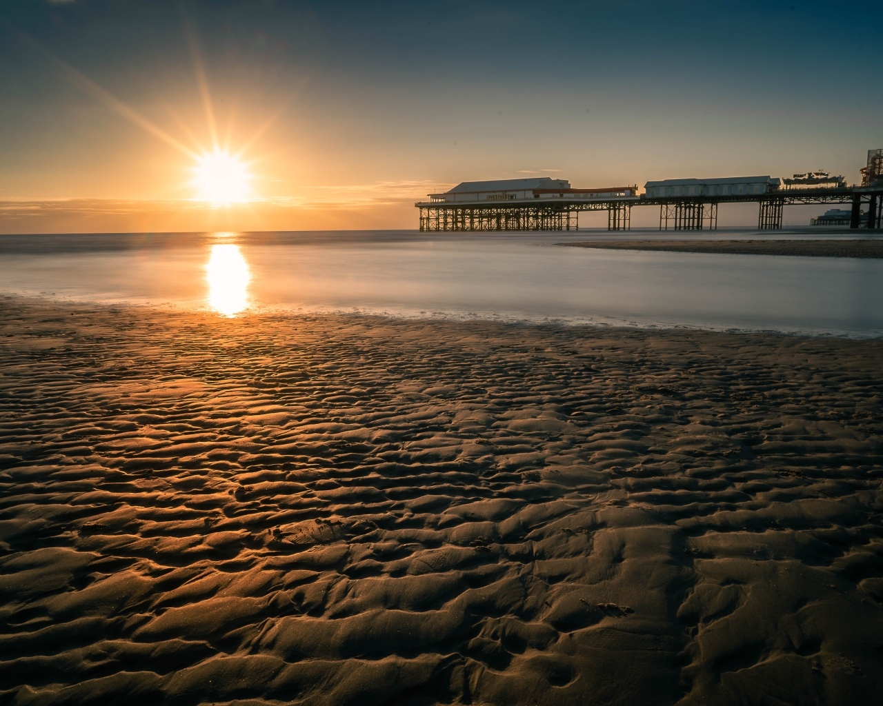 Мокрый песок на берегу моря на закате