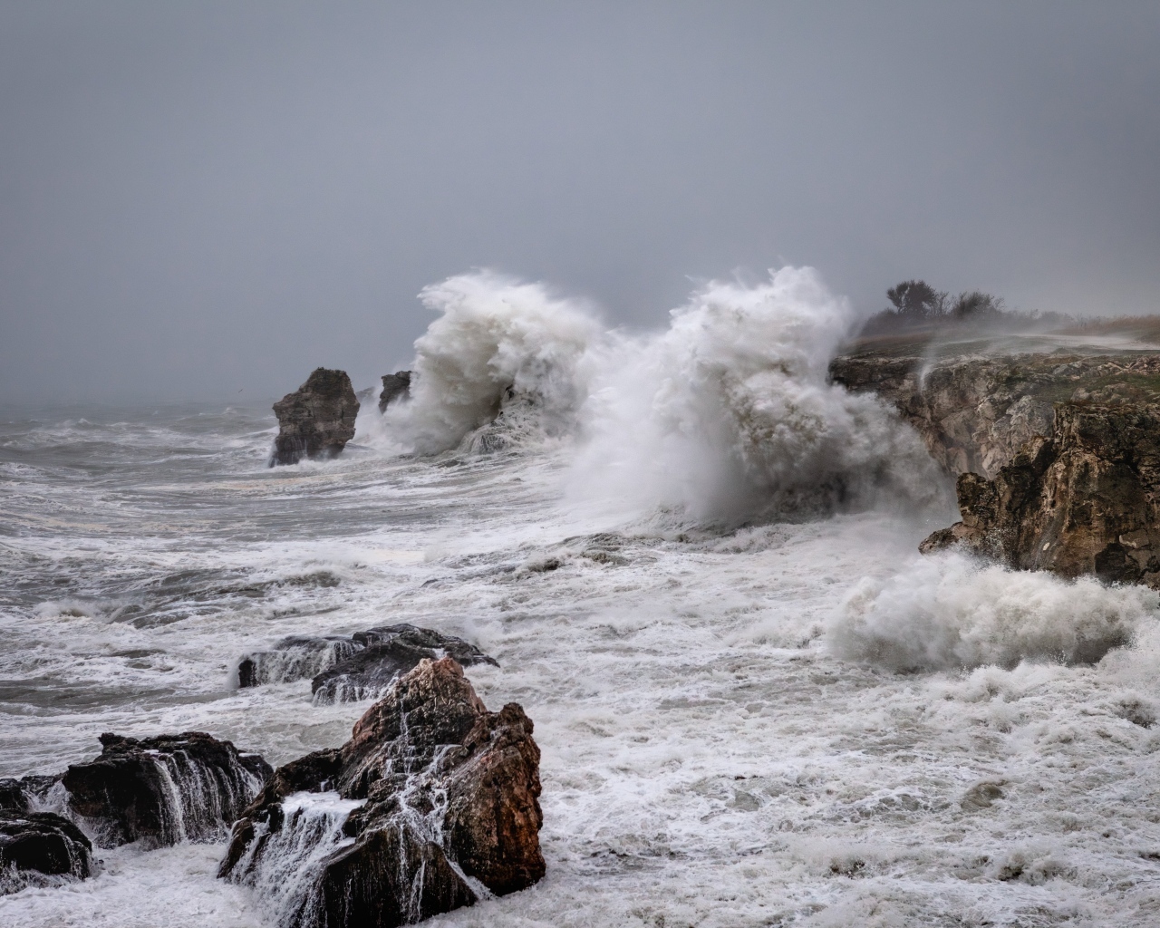 Белые пенные волны бьются об камни во время шторма