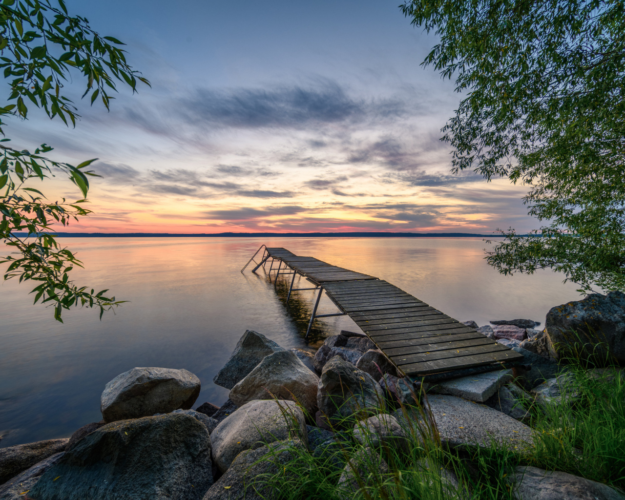 Старый деревянный пирс у озера на закате