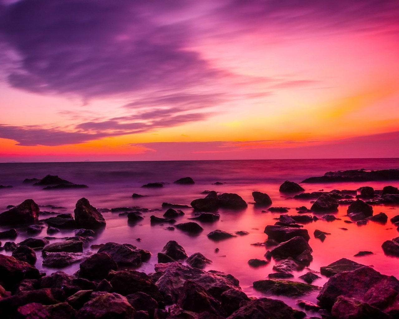 Розовый закат на каменном берегу моря