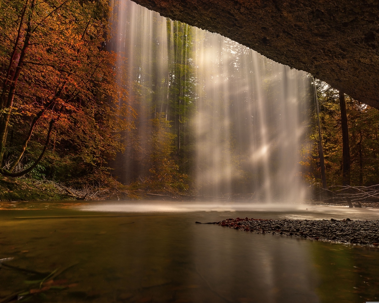 Водопад стекает со скалы в осеннем лесу