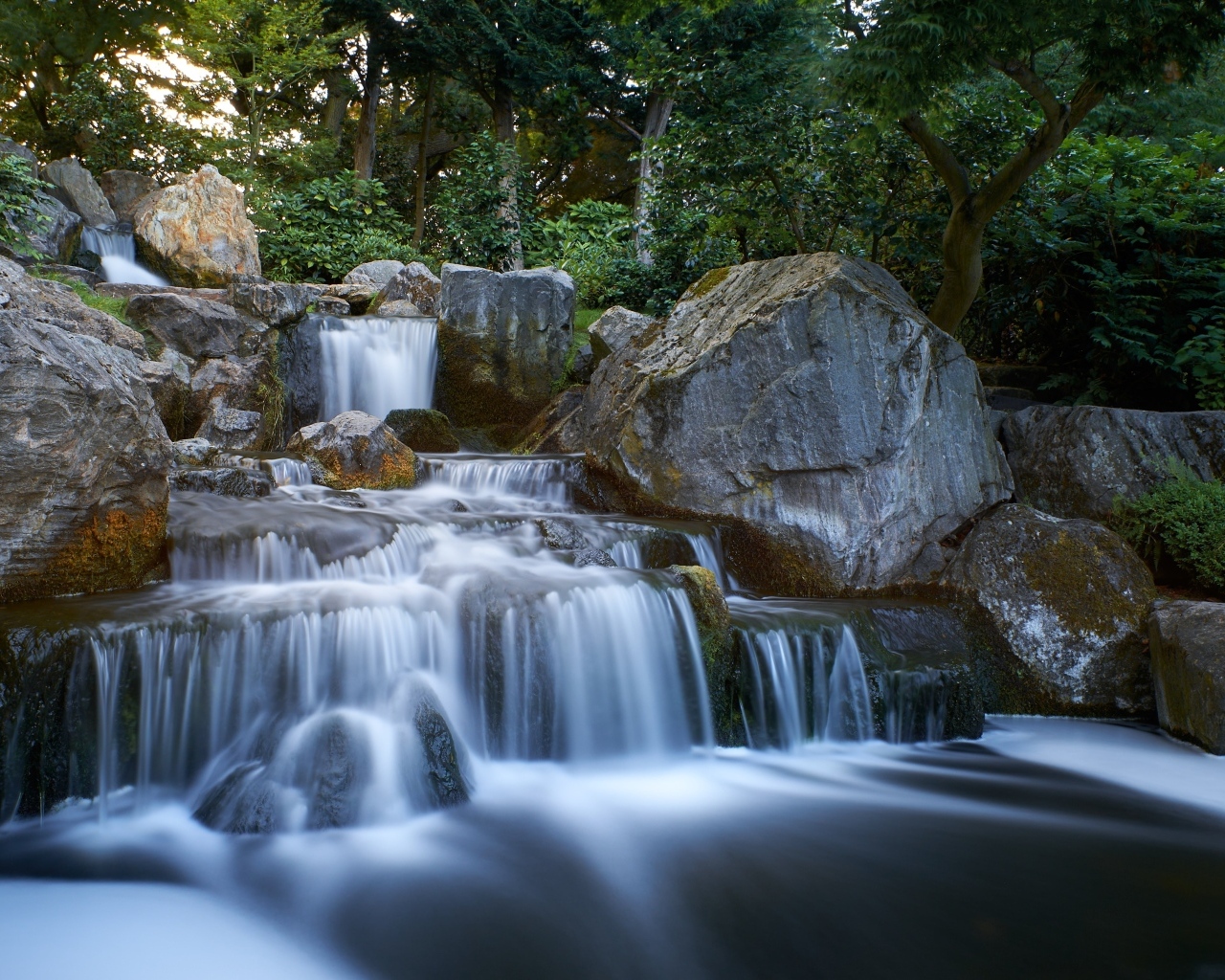 Водопад стекает по большим холодным камням в лесу