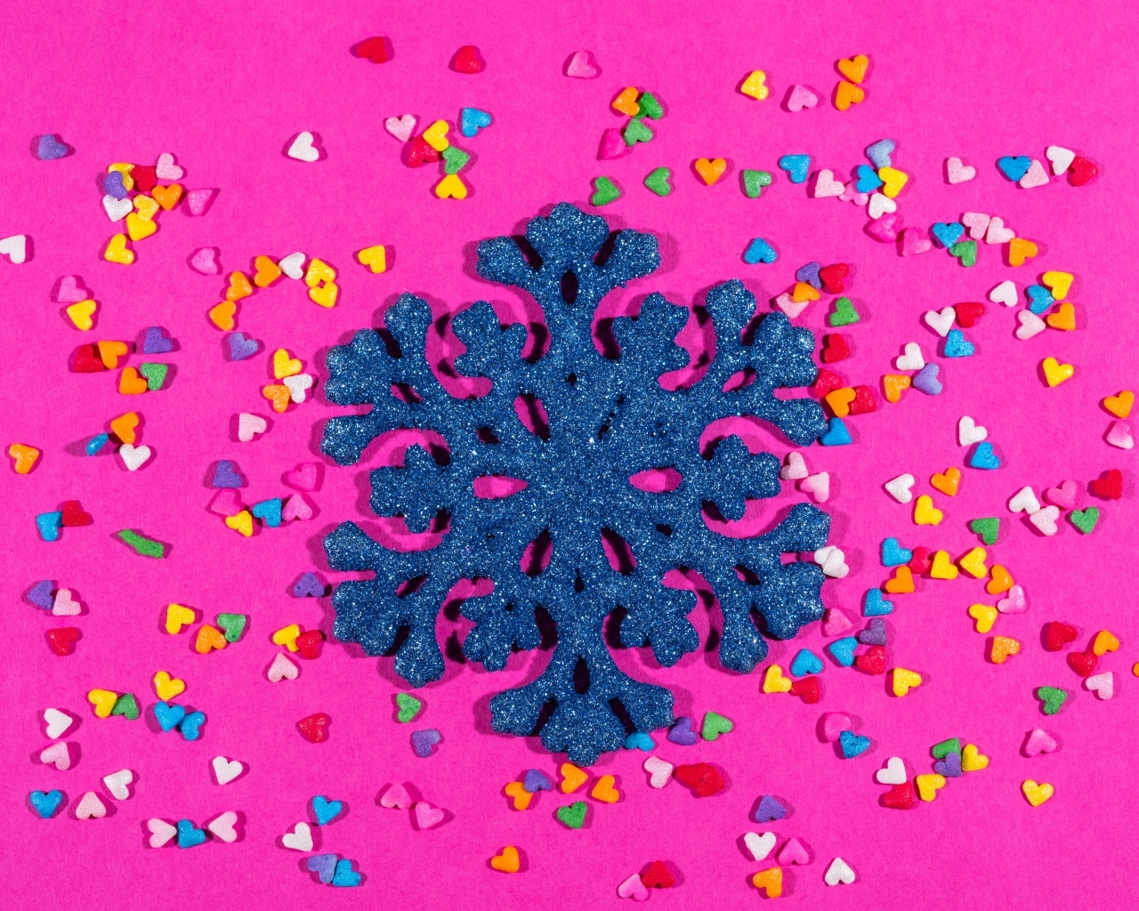 Большая синяя снежинка на розовом фоне с сердечками