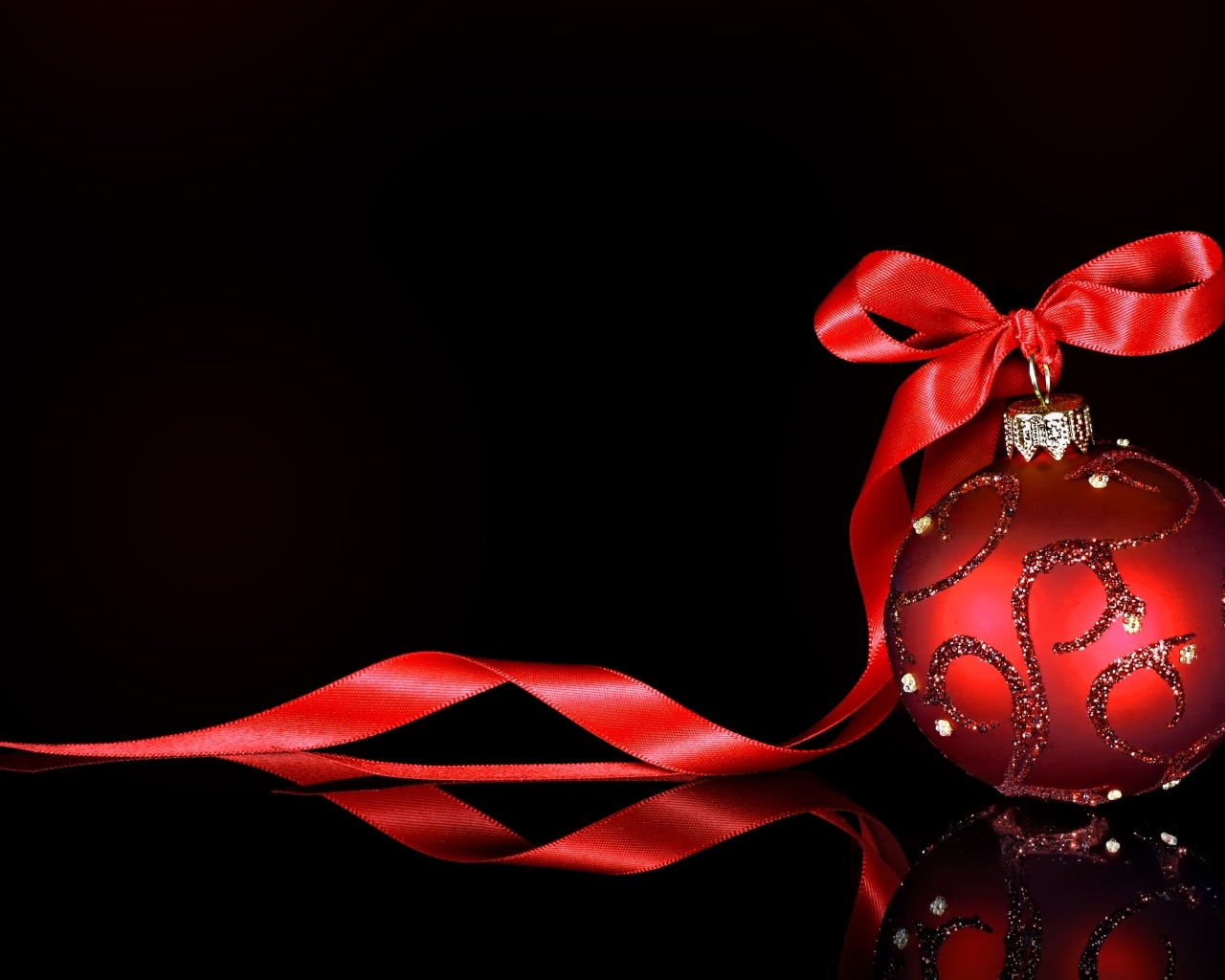Красный елочный шар с лентой на черном фоне