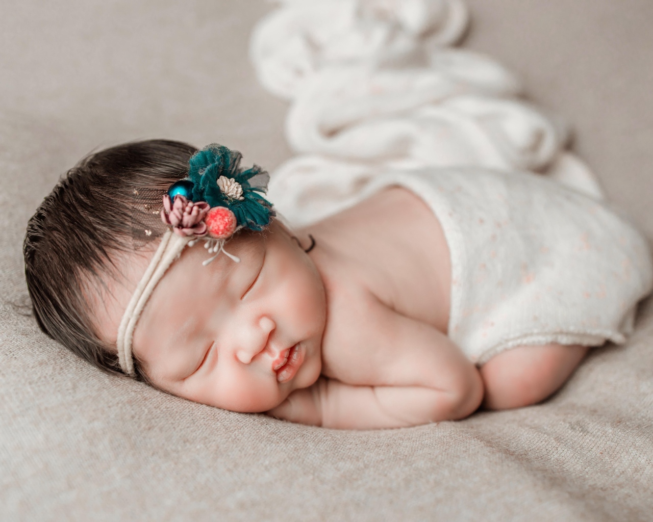 Новорожденная девочка азиатка спит на сером покрывале