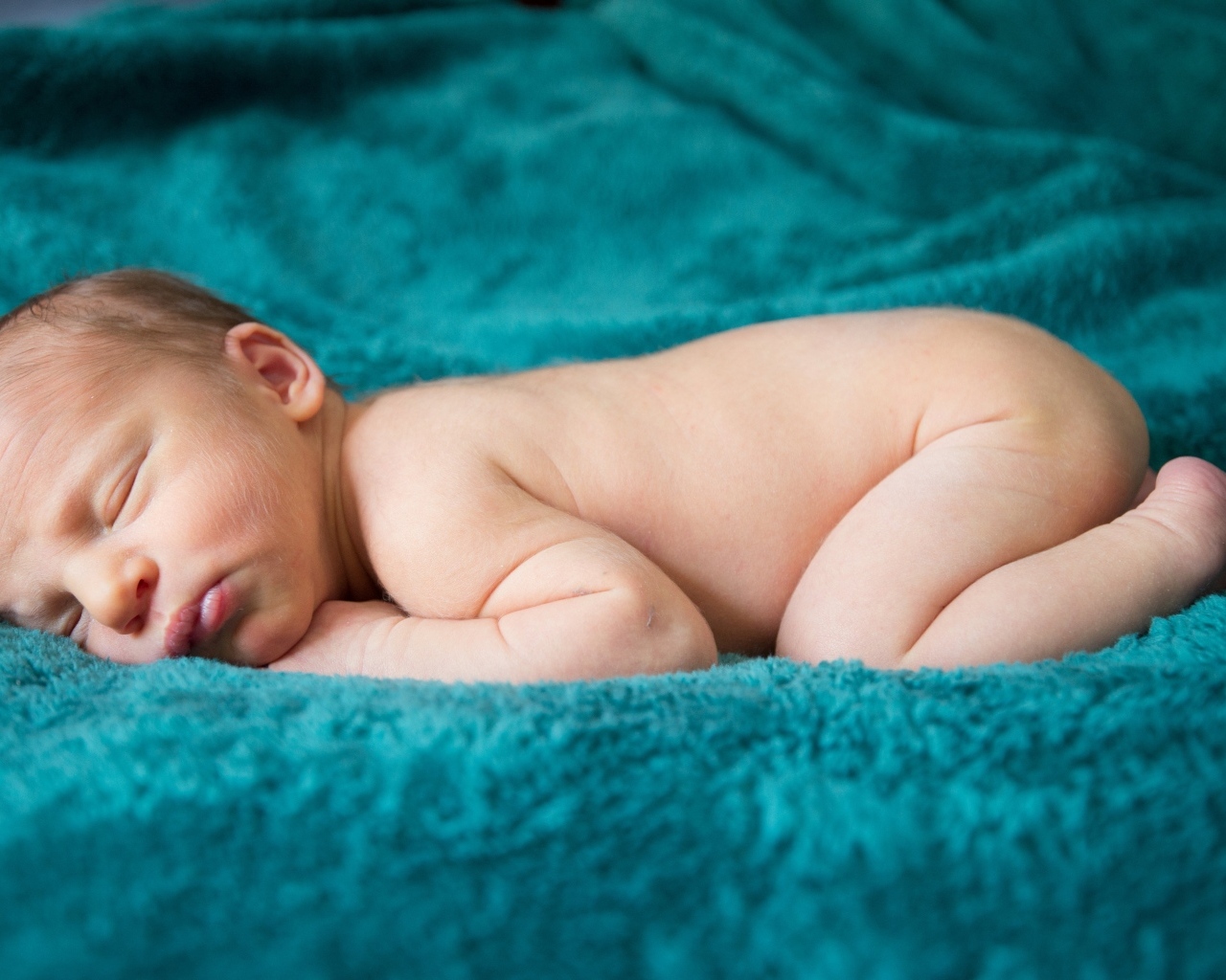 Грудной ребенок спит на синем пледе