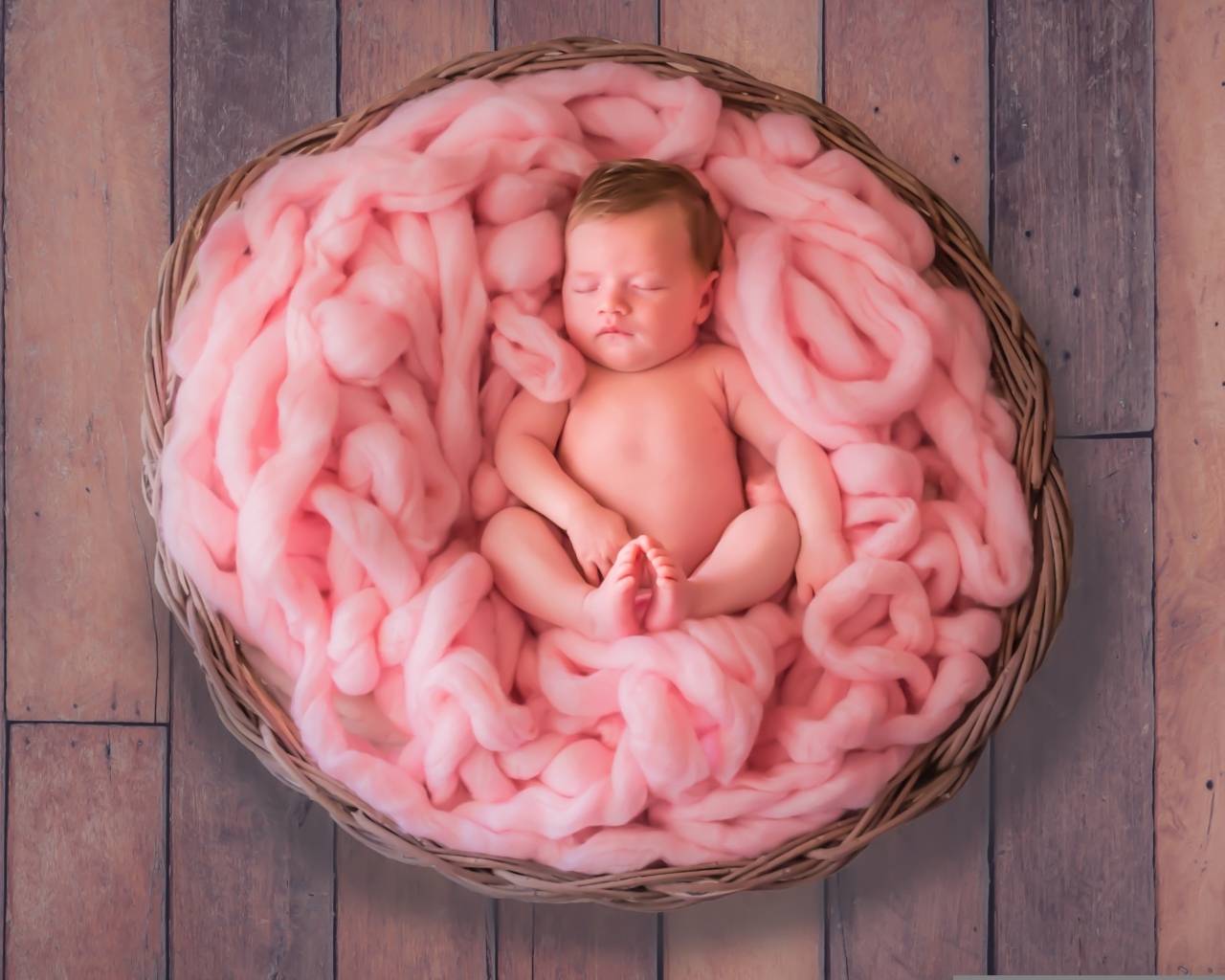 Ребенок спит в корзине с розовым покрывалом