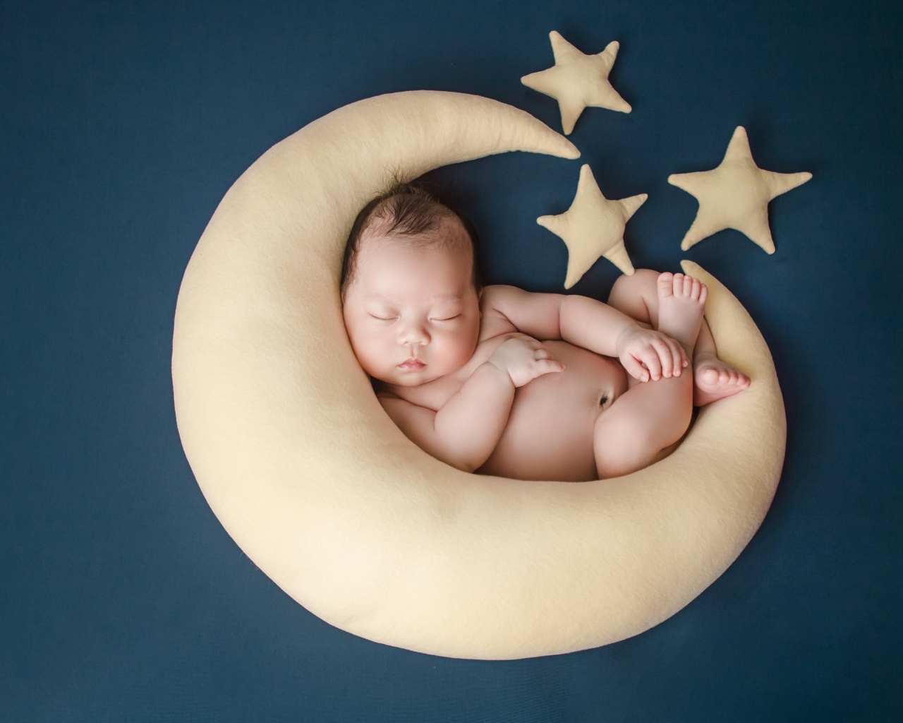 Ребенок спит на игрушечном месяце