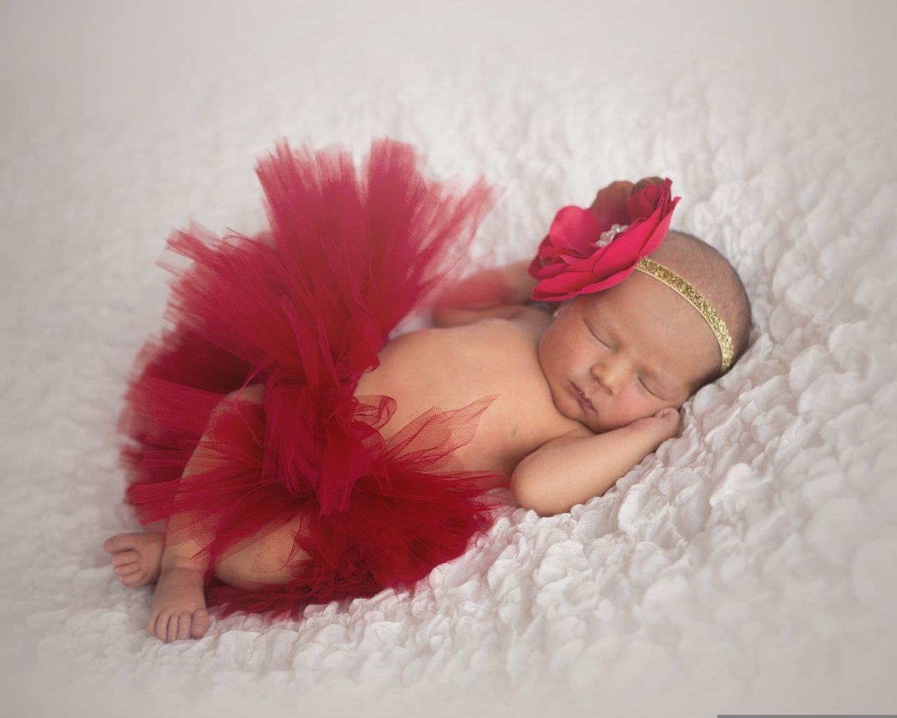 Красивая пышная красная юбка и бант на спящей малышке