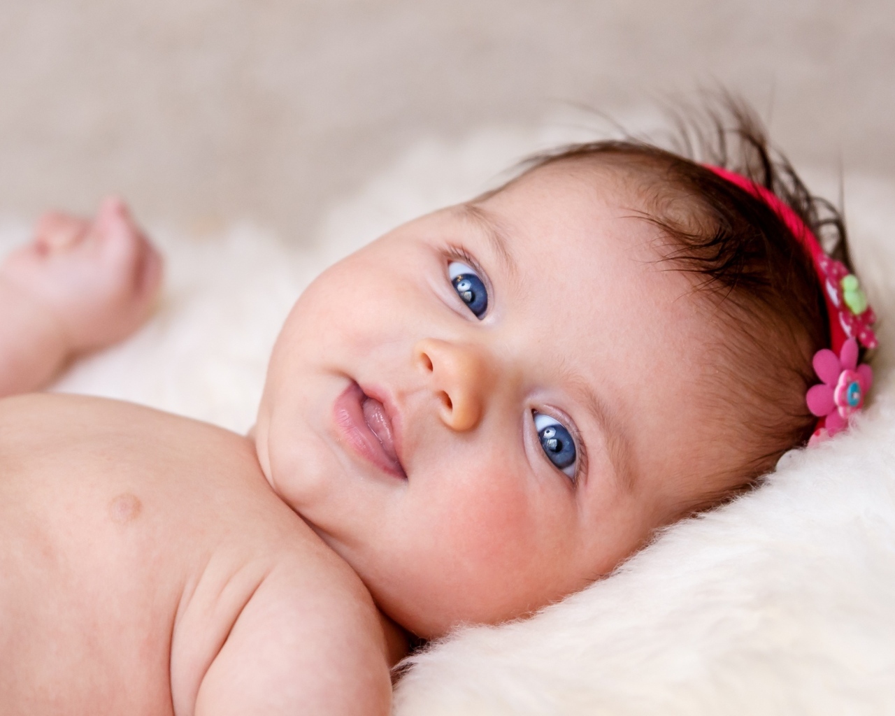 Голубоглазая новорожденная малышка с цветком на голове