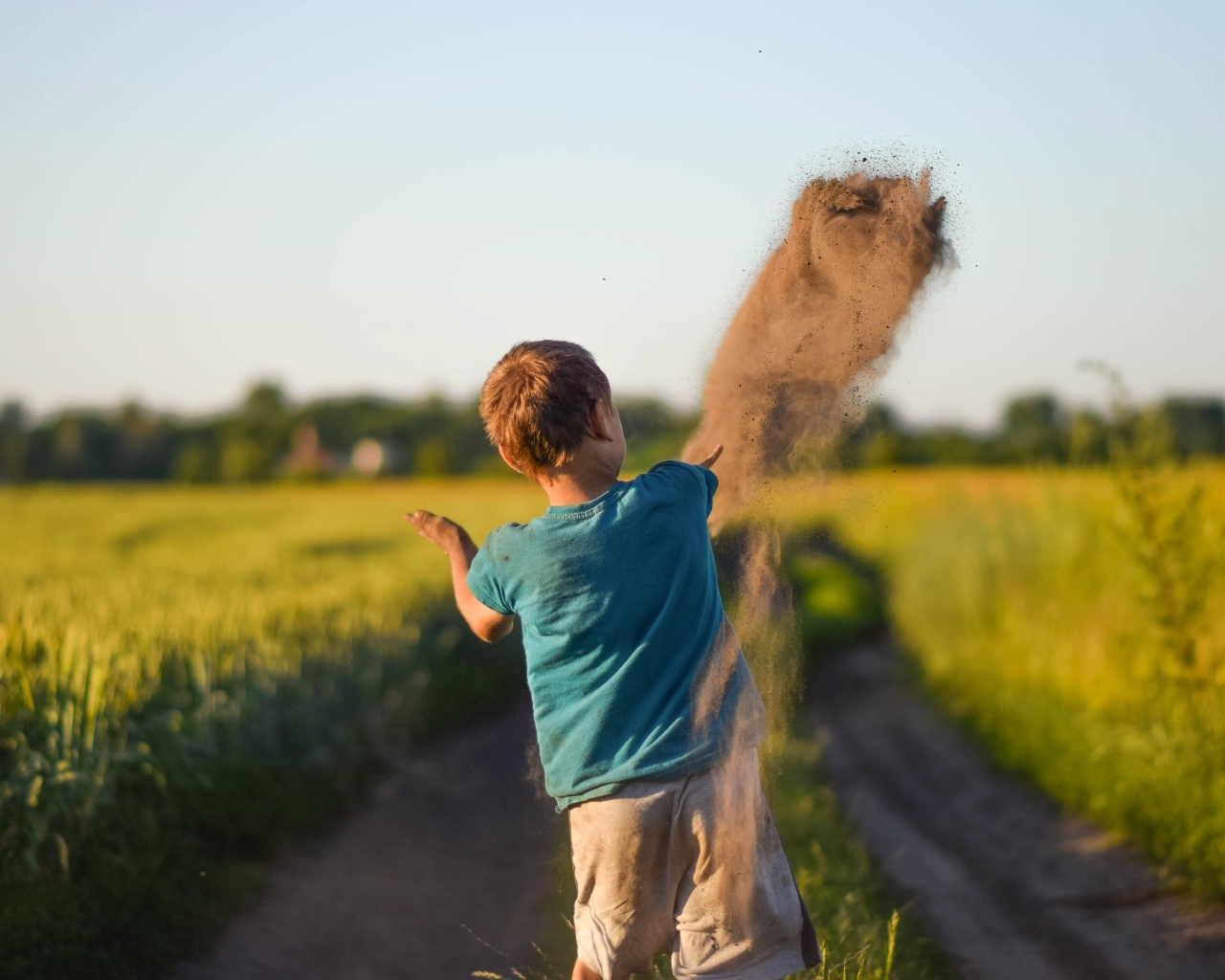 Мальчик бросает песок на дороге