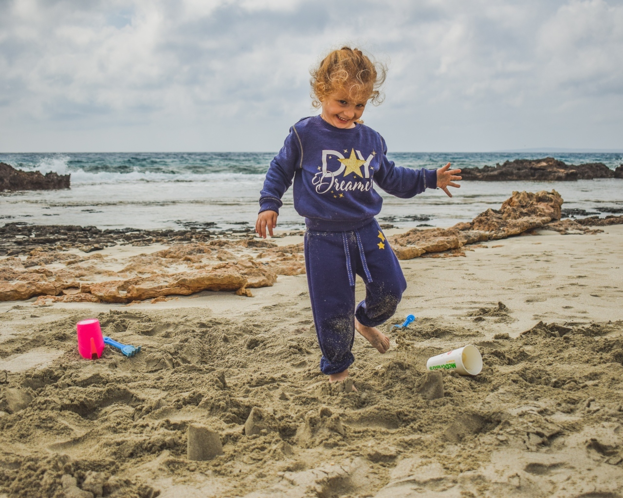 Веселая девочка играет на песке на пляже
