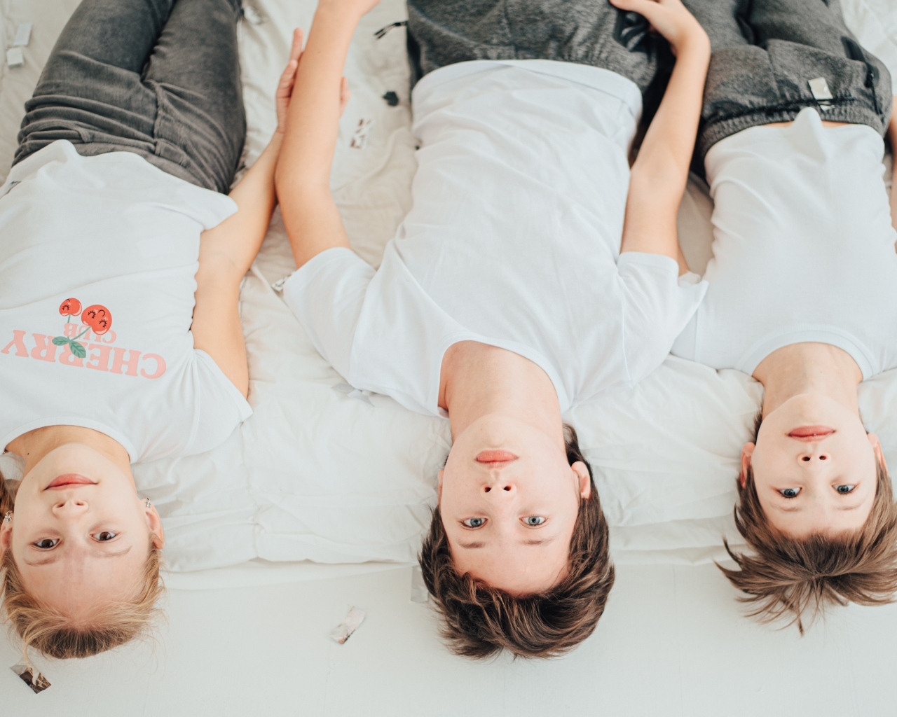 Дети в белых футболках лежат на кровати