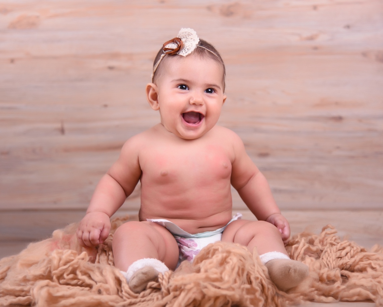 Милый улыбающийся ребенок на фоне деревянной стены