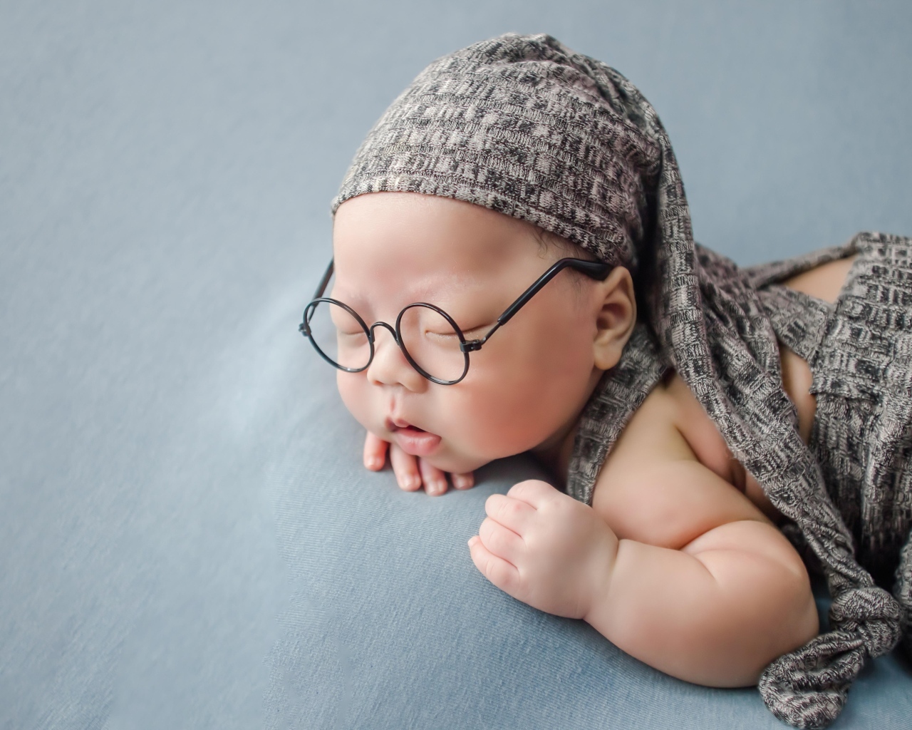 Забавный малыш в очках одет в серый костюм