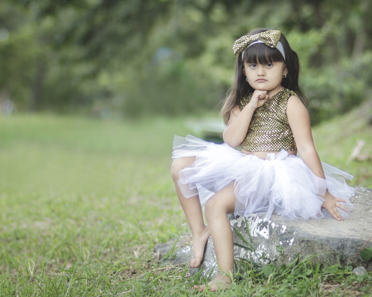 Девочка в красивом платье сидит на камне