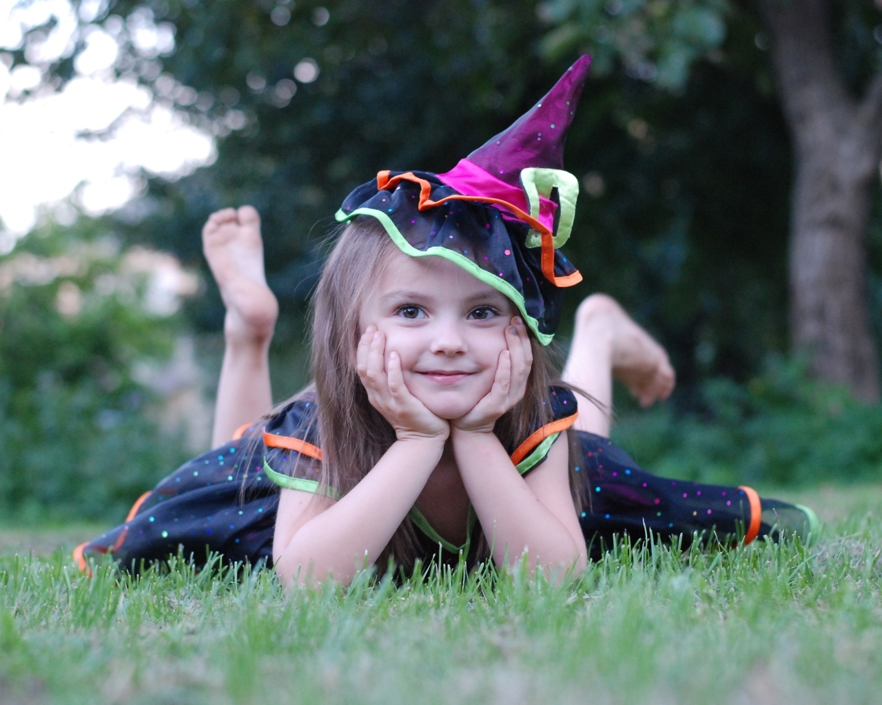 Девочка в костюме лежит на зеленой траве