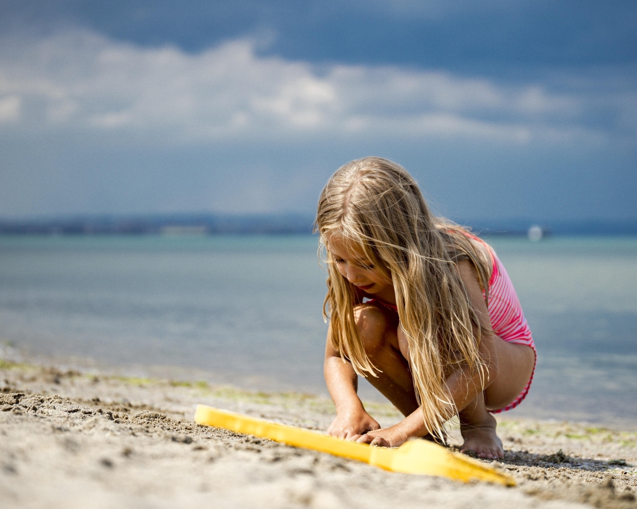 Девочка играет на песке у моря