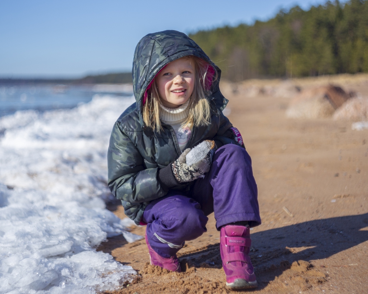 Девочка сидит у замерзшего озера 