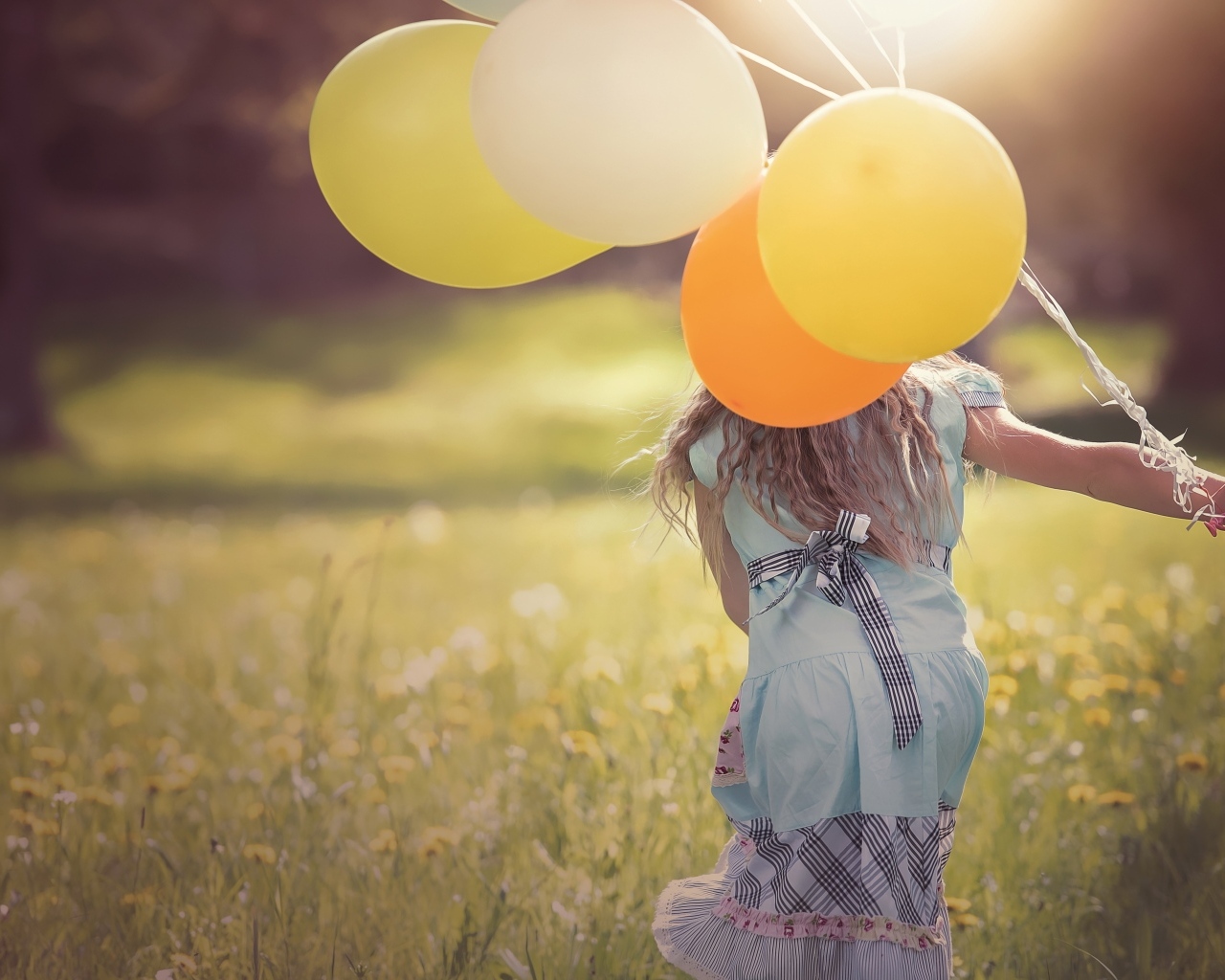 Девочка с шариками бегает по траве