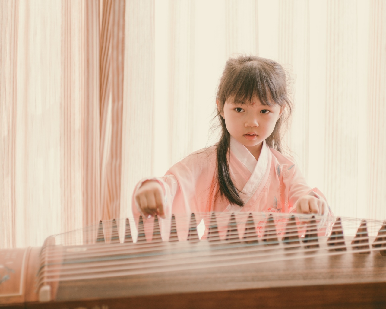 Маленькая девочка азиатка играет на музыкальном инструменте