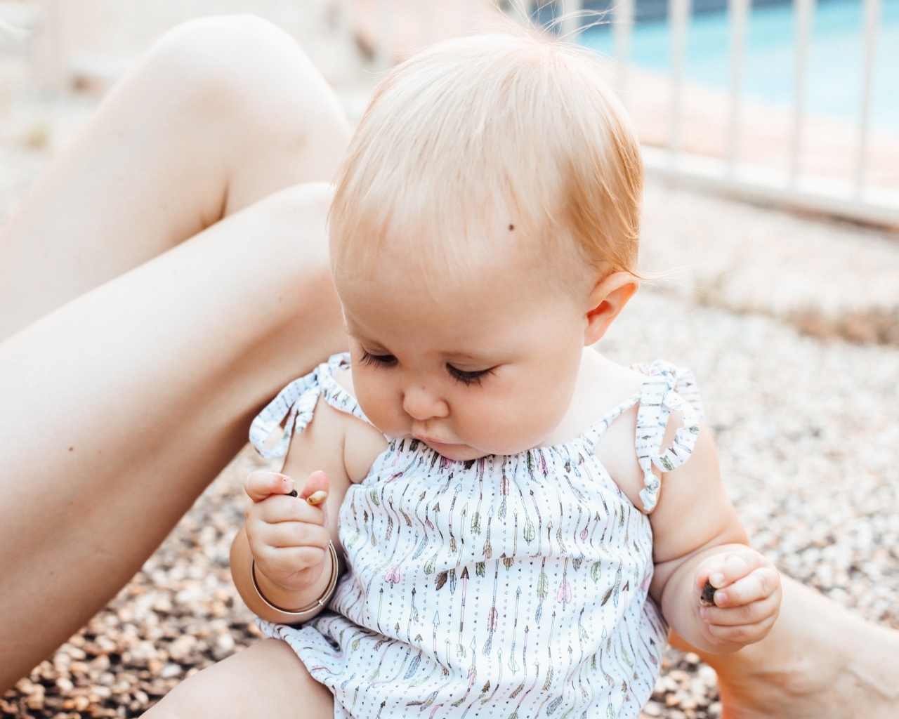 Маленькая светловолосая девочка сидит на песке