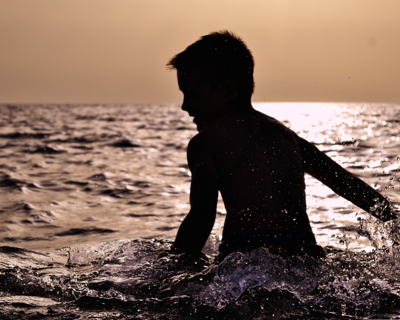 Маленький мальчик купается в воде летом